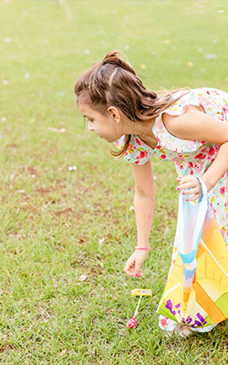 little girl picking up a piece of candy outside